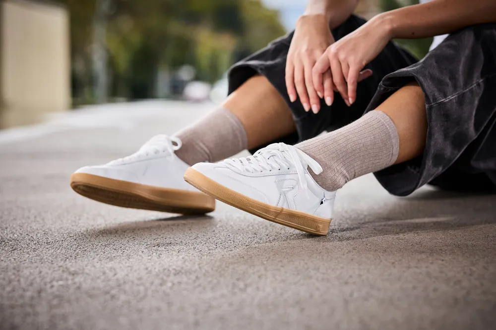 a person sitting on the ground wearing white Rieker shoes